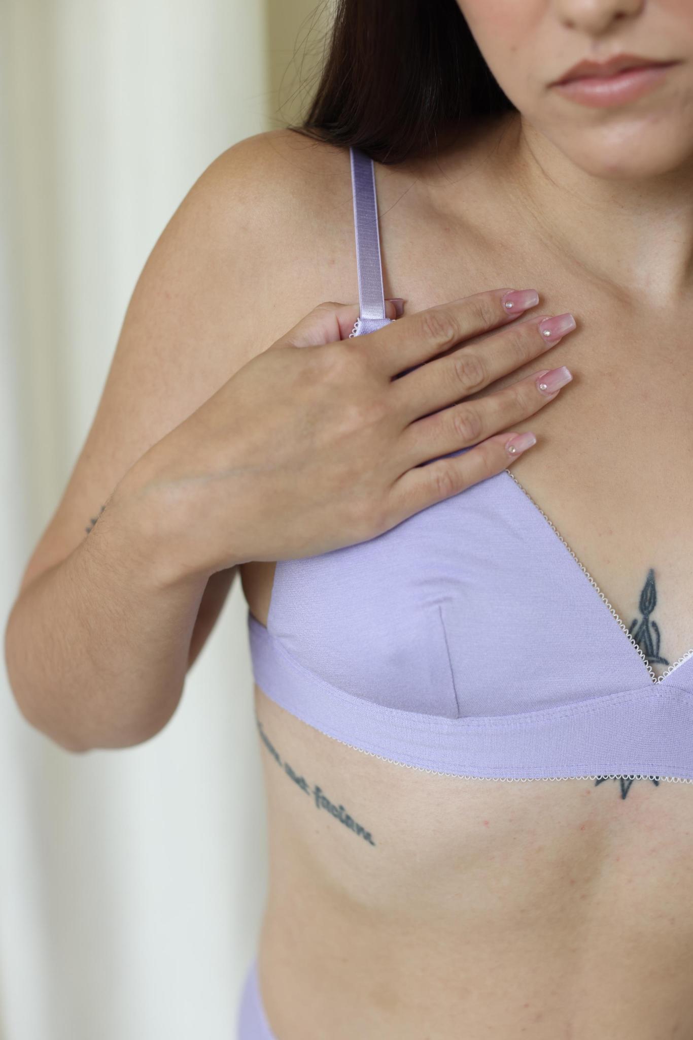 Person wearing a light purple bra with a neutral background